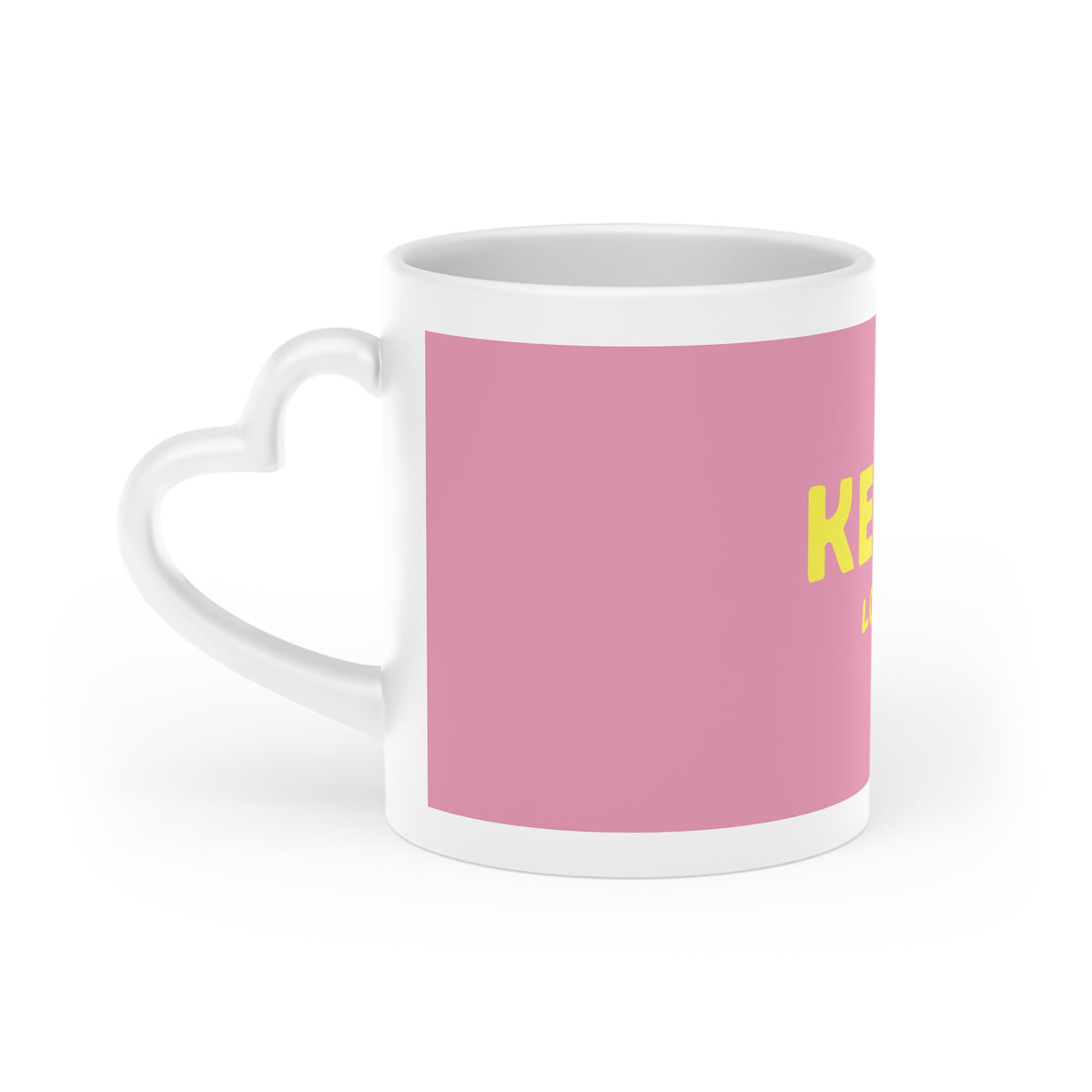 Seitenansicht der rosa Kefir Lover Keramiktasse mit gelbem Aufdruck und weißem herzförmigem Henkel.