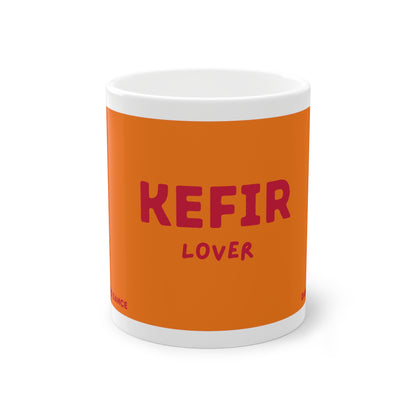 Orangefarbene Kefir Lover Keramiktasse von Dancing Microbes mit dunkelrosa Schriftzug „KEFIR LOVER“ auf weißem Hintergrund.