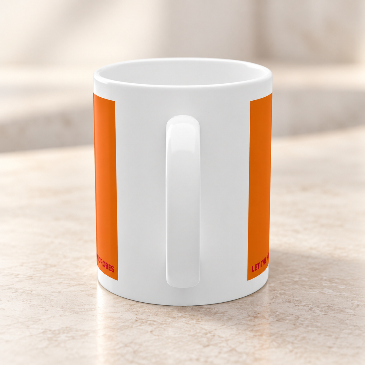 Rückseite der Kefir Lover Keramiktasse mit weißer Keramikfläche und orangefarbenen Druckelementen auf einer hellen Arbeitsfläche.