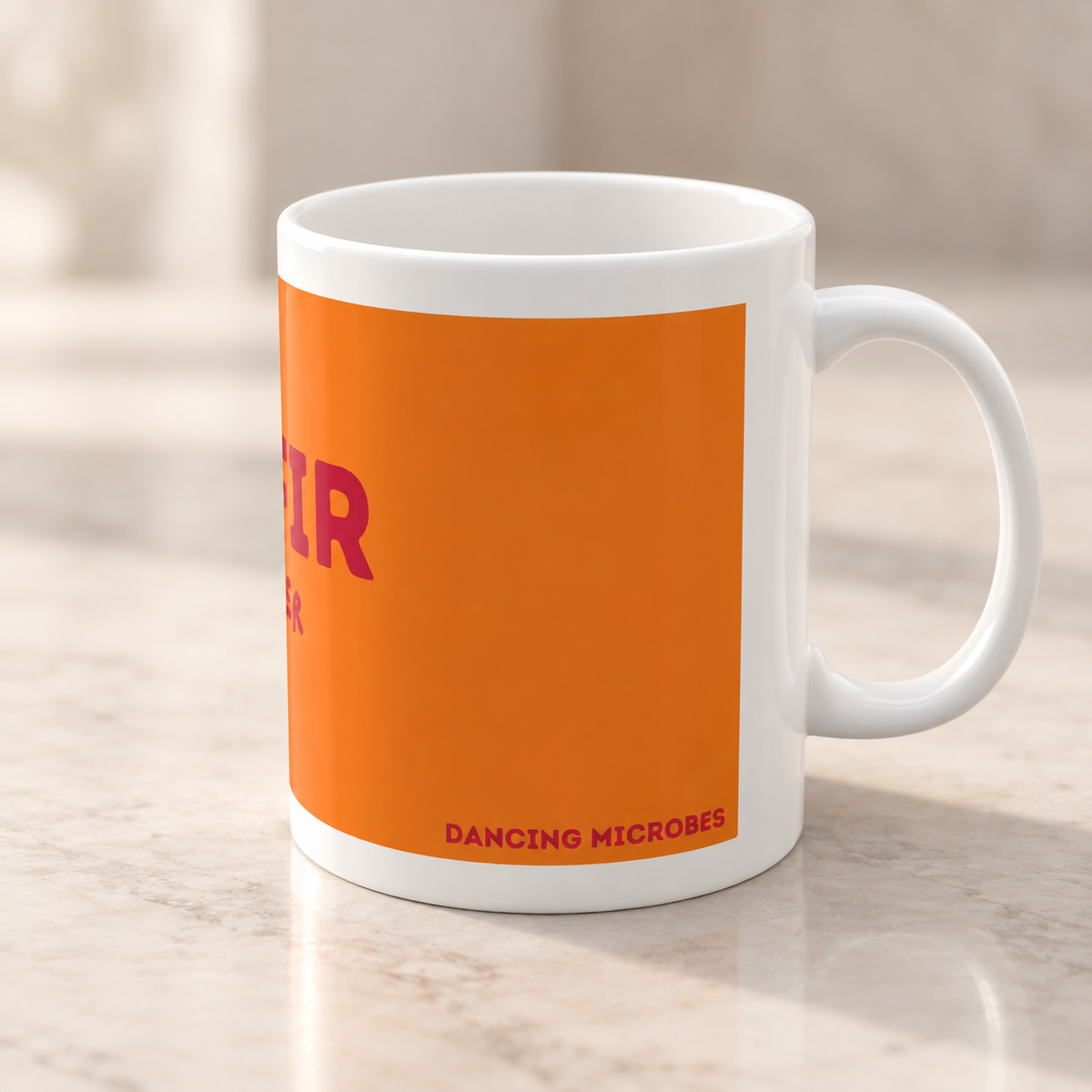 Seitenansicht der orangefarbenen Kefir Lover Keramiktasse mit weißem Henkel rechts auf einer hellen Arbeitsfläche.