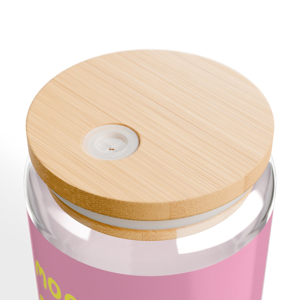 Nahaufnahme des Bambusdeckels mit Öffnung für den Trinkhalm auf dem rosa bedruckten More Kefir Por Favor Trinkglas.