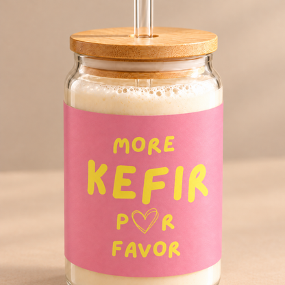 Nahaufnahme des More Kefir Por Favor Trinkglases mit gelbem Schriftzug auf rosa Hintergrund und Bambusdeckel.
